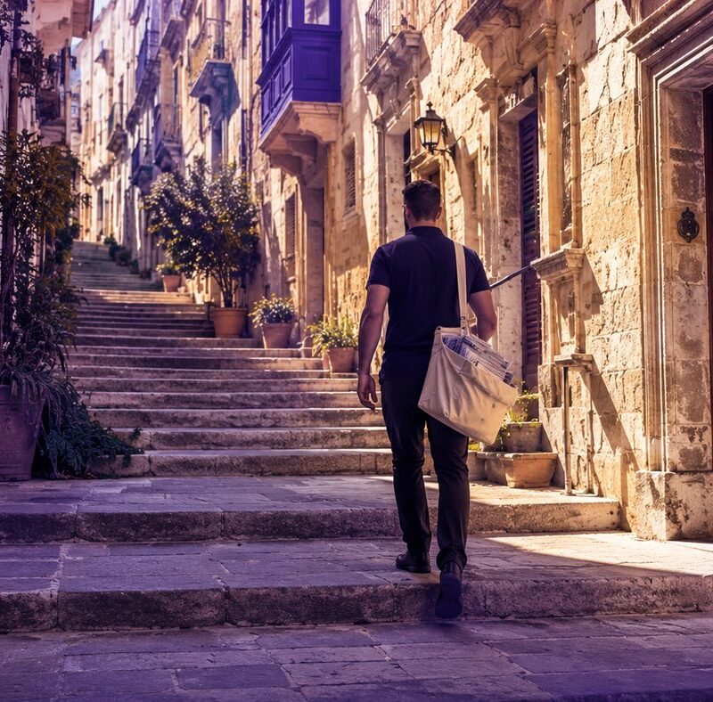 PostPro distributor delivering leaflets door-to-door on a Maltese street